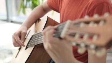 Kanepede oturup gitar çalan yakışıklı bir çocuğun portresi. Telli müzik aleti. Müzik hayatı.