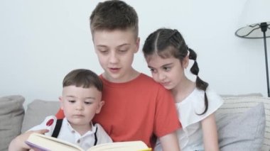 Mutlu çocuklar kanepede dinleniyorlar ve kitap okuyorlar. Erkek ve kız kardeşler birlikte okuyorlar. Akıllı çocuklar. Mutlu aile