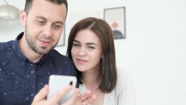 Gelukkig Paar Ontspannen Bank Thuis Echtgenoot Houdt Smartphone Handen Lachen — Stockvideo
