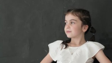 Stüdyoda siyah arka planda küçük bir kızın portresi, kameranın lensine bakıyor ve gülüyor. Neşeli çocuk.