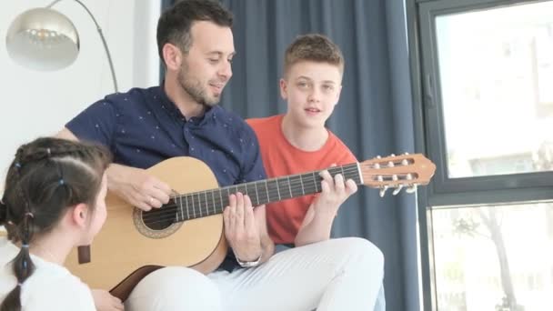 Glad Pappa Spelar Gitarr För Sina Barn Som Sitter Soffan — Stockvideo