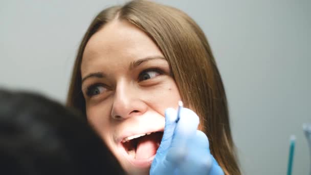 怖がった少女は現代の診療所で歯を治療する 歯医者の臆病と恐怖 歯医者は患者の歯を調べ — ストック動画