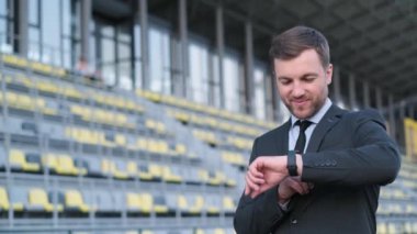 Kafkas işadamının akıllı saate bakan portresi. Gülümse yakışıklı başarılı iş adamı resmi takım elbiseli açık havada