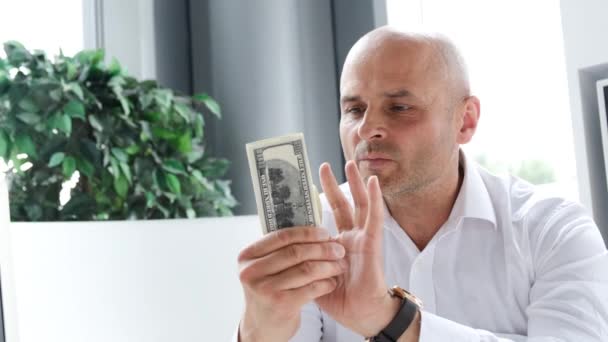 幸せなビジネスマンはオフィスの机に座っている間ドルを数える 彼の手に金を持つ会計士 — ストック動画