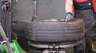 Lastik dengeleyici araba servisi. Lastik tesisatçısı lastiği arabanın diskine takıyor. Araba tamircisi. 4k video