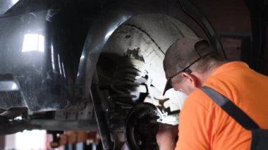 El feneri olan bir araba tamircisi arabanın durumunu kontrol eder. Atölyedeki asansörde arızalı bir araba var. Araba yardımı