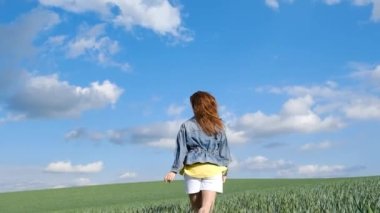 Sevimli ve mutlu bir kız buğday tarlasında elinde bir buket çiçekle neşeyle koşar. Mutlu bir çocukluk. Doğanın tadını çıkar