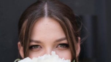 Gri arka planda güzel gelinin sevgi dolu gözlerini kapat. Gelin buketi beyaz çiçekler