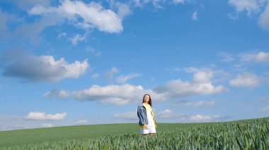 Güzel, yalnız bir kız kollarını açmış yeşil bir tarlanın ortasında duruyor. Kendini özgür hissediyor ve doğanın tadını çıkarıyor. 4k video