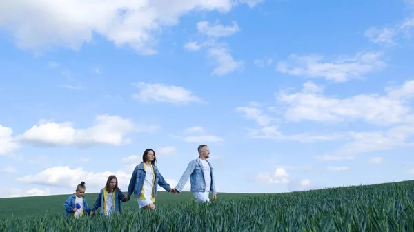 Happy family of farmers with son and daughter walking on a wheat field. Family holding hands and enjoying nature outdoors. Slow motion