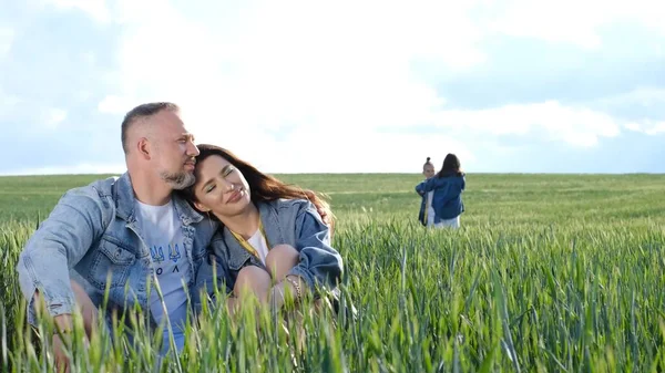 Happy family of farmers with son and daughter walking on a wheat field. Family holding hands and enjoying nature outdoors. Slow motion