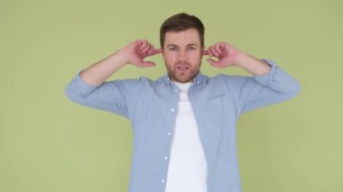 Stüdyoda arka planda izole edilmiş beyninde patlama jesti gösteren bir adam. Çocuk parmaklarıyla kulağını kapadı ve bağırdı. 4k video