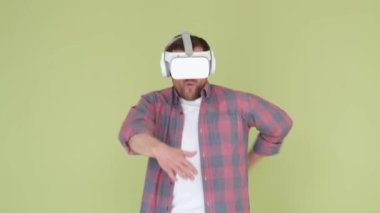 Man with virtual reality glasses dancing in the studio on a yellow-green background. Funny dance of a man