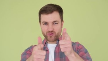 Close up of male killer, he makes imitation shots isolated on background in studio, shots of a gun with his hands in the studio