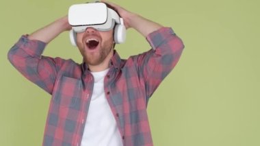 A surprised man in a VR headset shakes his head. Modern virtual reality technologies. Studio shot on olive background