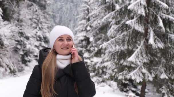 Een Vrouw Loopt Het Winterbos Praat Een Mobiele Telefoon Kijkt — Stockvideo
