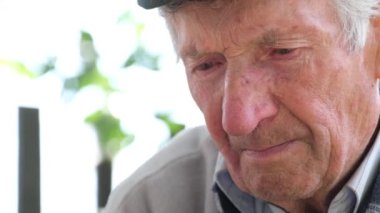 Portrait of a crying old grandfather looking down, he is depressed and sad. Problems in old age. Lonely grandfather in a shelter