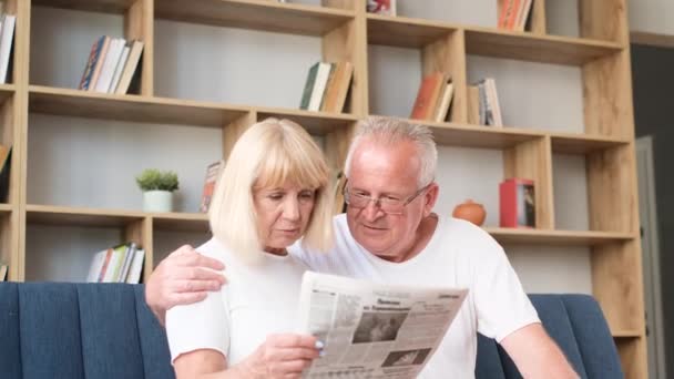 European Retired Couple Reading Latest Newspaper Hugging While Sitting Sofa — Stockvideo