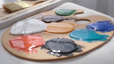 Sanatçılar atölyesi, işyeri, güzel sanatlar. Ahşap bir palette çok renkli akrilik boya ve aletler. Sanatçılık ve iş kavramı