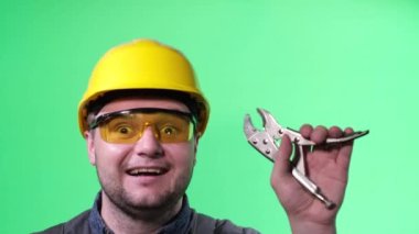Kromakey arka planında, elinde aletlerle genç bir elektrik mühendisi. Tamirat ve tamirat konsepti. Elinde pense olan bir adam.