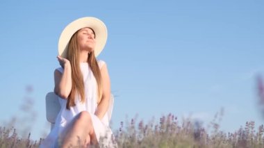 Young girl in lavender fields on a sunny day in the countryside. Pretty woman sitting on lavender field at sunny day