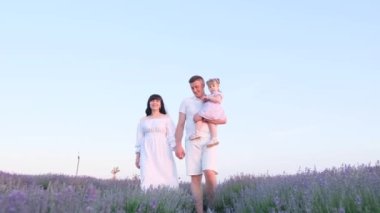 Young family walking on the purple flowers field. Happy family outdoors.