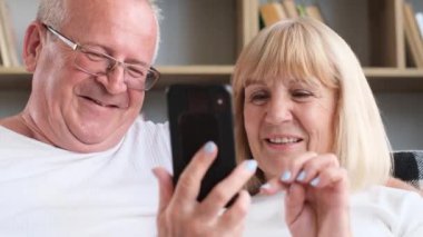 Close-up of the faces of a husband and wife searching the Internet. Happy and smiling elderly couple.