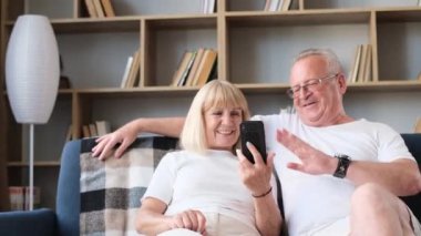 Old man and wife communicate with relatives on Weber, WhatsApp and messengerand wave hello. Advanced communication technologies.