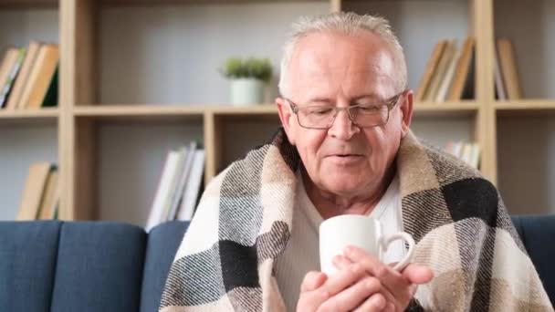 Old Gray Haired Man Sits Sofa Covered Blanket Drinks Tea — Stok Video