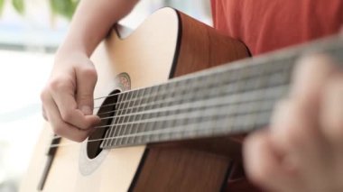 A teenage boy plays the guitar. A hand plays on the strings of a guitar. Music as a hobby. Learning to play the guitar