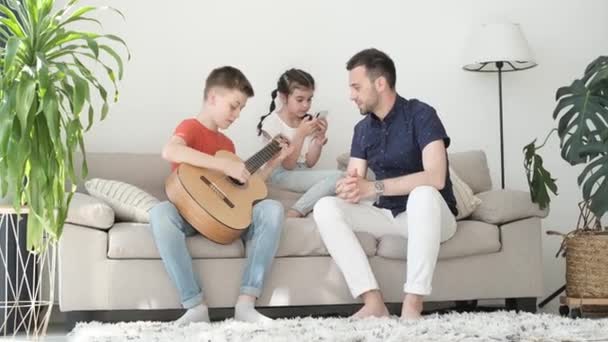 Dad Two Children Family Weekend Home Teenage Son Plays Guitar — Stock video