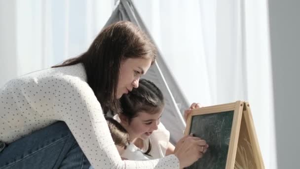 Young Mother Draws Chalk Easel Together Her Little Son Daughter — Stok video