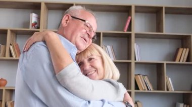 Elderly couple in love slow dancing at home. Happy husband and wife hug. Love in old age