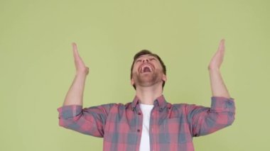 Handsome guy in a shirt looking up and shouting with happiness Yes. Surprised and happy man raised his hands up, close up. 4k video