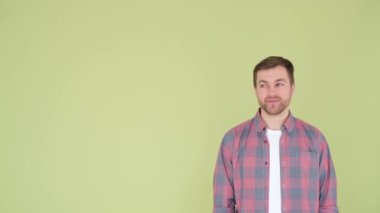 Young attractive smiling funny man isolated on yellow background, studio portrait. People lifestyle concept sincere emotions. Layout copy space. Pointing index finger to the side. 4k video