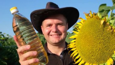 A European farmer demonstrates a sunflower oil product right in the field. Agriculture worker on a sunflower plantation. 4k video