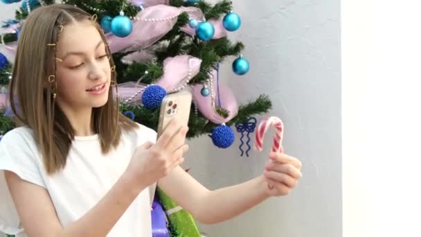 Teenage Child Takes Pictures Caramel Candies Smartphone Christmas Tree Home — Stockvideo