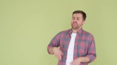 Handsome man in red shirt funny dancing isolated on background in studio, man rejoices and dances to modern music