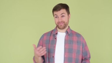 Surprised man spreads his arms, saying no, no. Studio shooting on a green-yellow background. 4k video