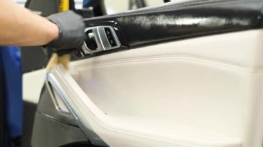 Car cleaning. Cleaning the leather elements in the car door. Professional car detailing.