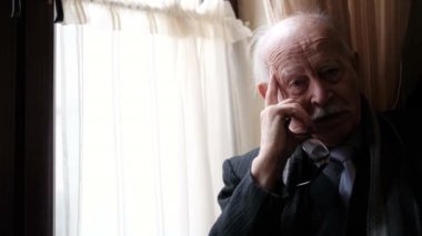 Portrait of a lonely old, elderly grandfather who has a headache and needs help, depressed retiree, close up