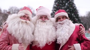 Three Santa Clauses walk the streets of New York. American Santa at work, they wave hello to the camera. Christmas mood concept