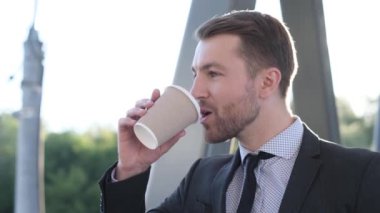 Closeup confident business man drinking coffee. Portrait of beautiful handsome man worker looking away outdoors. 