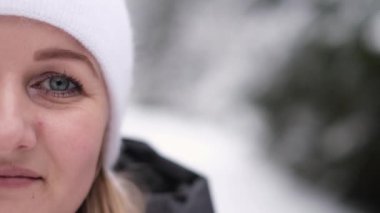 Close up portrait of a beautiful girl in a white hat in the middle of the winter forest, she looks straight. christmas forest. Beautiful face of a girl. Winter concept