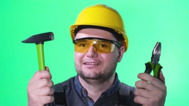 Professional male builder on green screen. he holds tools in his hands and smiles at the camera - green screen studio