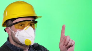Male builder in respirator and goggles on green background with colored key. goggles and respirator, chemical worker