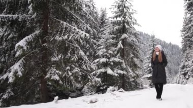 A young girl walks on a trail in a snowy forest. Beautiful winter time outdoors. 