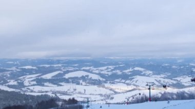 Time lapse on snowy mountains with ski lift at ski resort. Ski lift cable car from top to bottom. Winter landscape with snowy mountains. Ski tourism concept