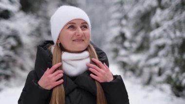 Super slow mo 240 fps, portrait of a beautiful European girl in the middle of a winter forest, she is wearing a white hat and looking up. A walk in the winter forest. Winter background