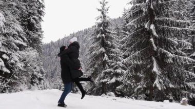 Couple in love among the winter forest. Winter park. Young couple fooling around in the middle of frozen trees, winter road in the woods